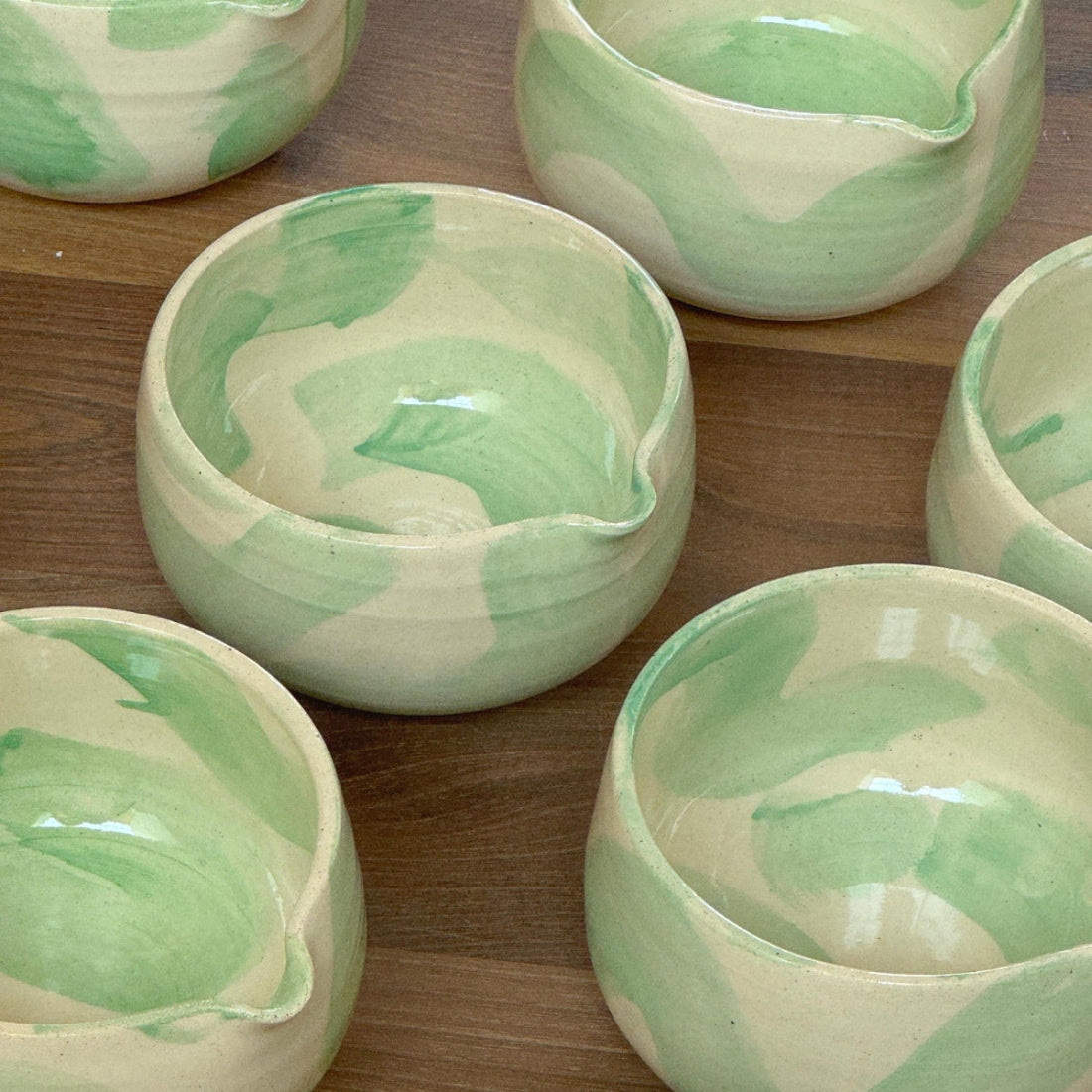 Set of ceramic bowls with green and white marbled pattern on a wooden surface