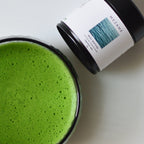 Green matcha tea in a glass with a container labeled 'MEZAME' on a white background