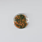 Small round dish with Mezame genmaicha green tea leaves on a gray background