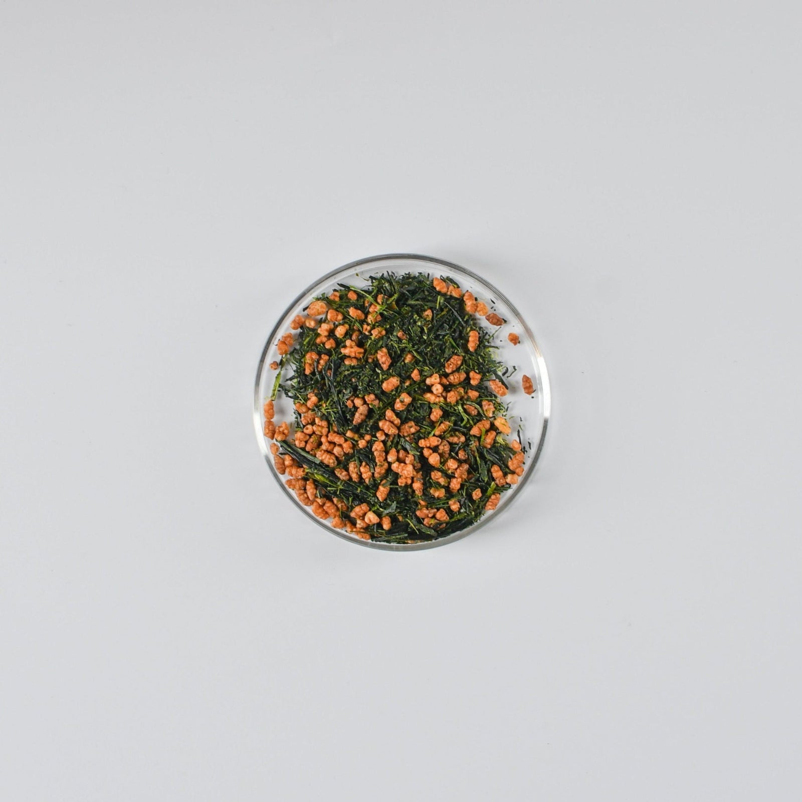 Small round dish with Mezame genmaicha green tea leaves on a gray background