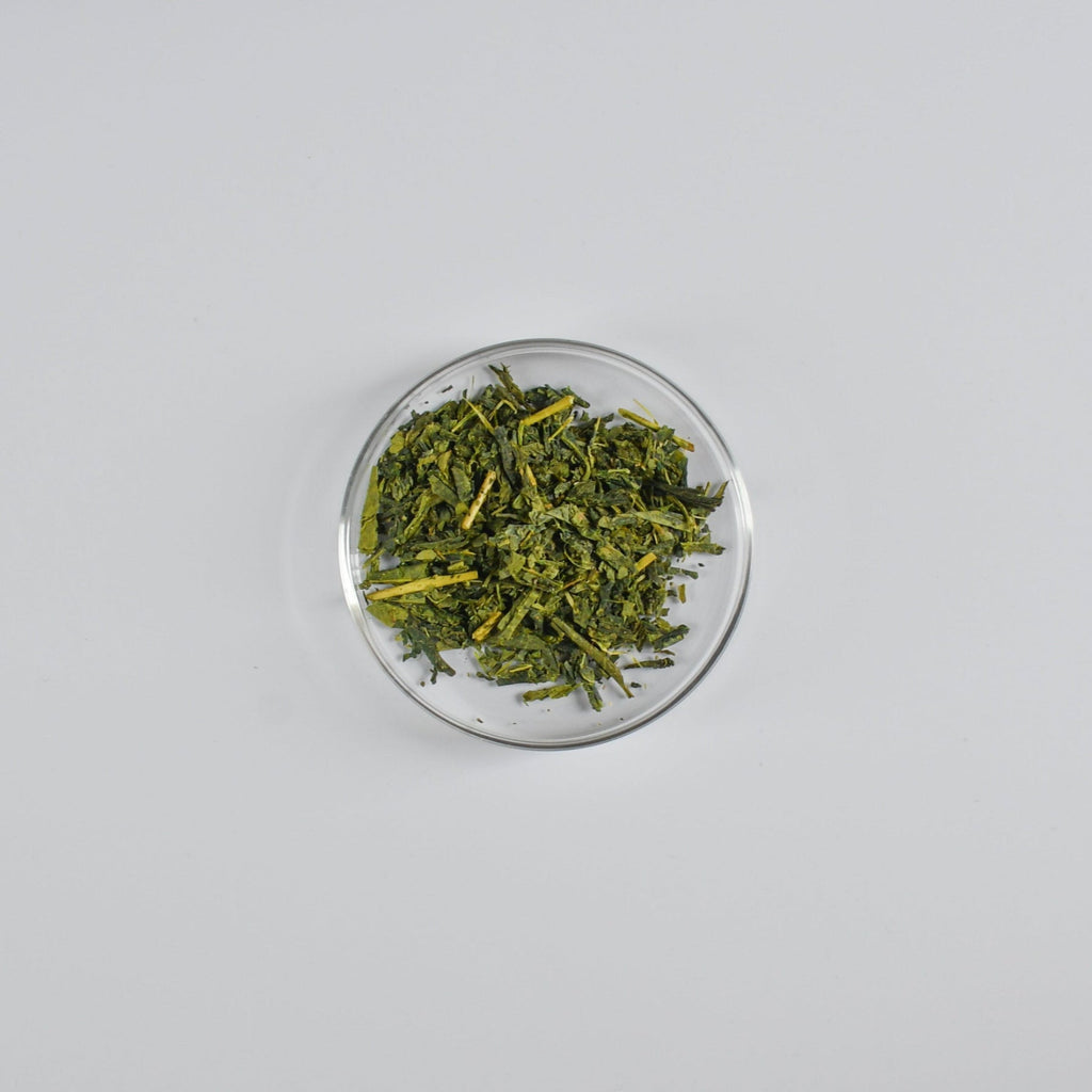 Sencha tea leaves in a clear glass bowl on a white background