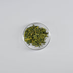 Sencha tea leaves in a clear glass bowl on a white background