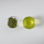Glass of sencha green tea with green tea leaves on a white background