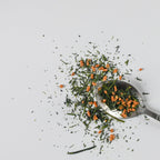 Spoon with Mezame genmaicha tea leaves on a white background