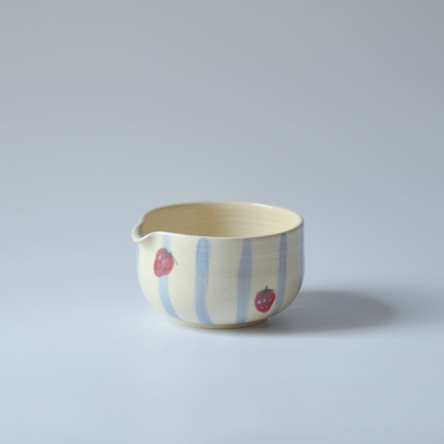 Ceramic bowl with strawberry design on a light gray background